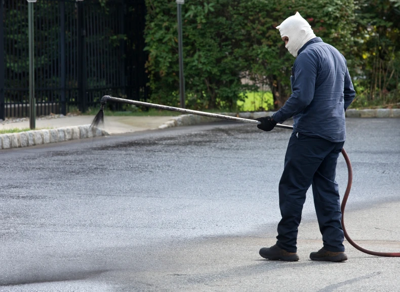 Person sealing pavement with tar